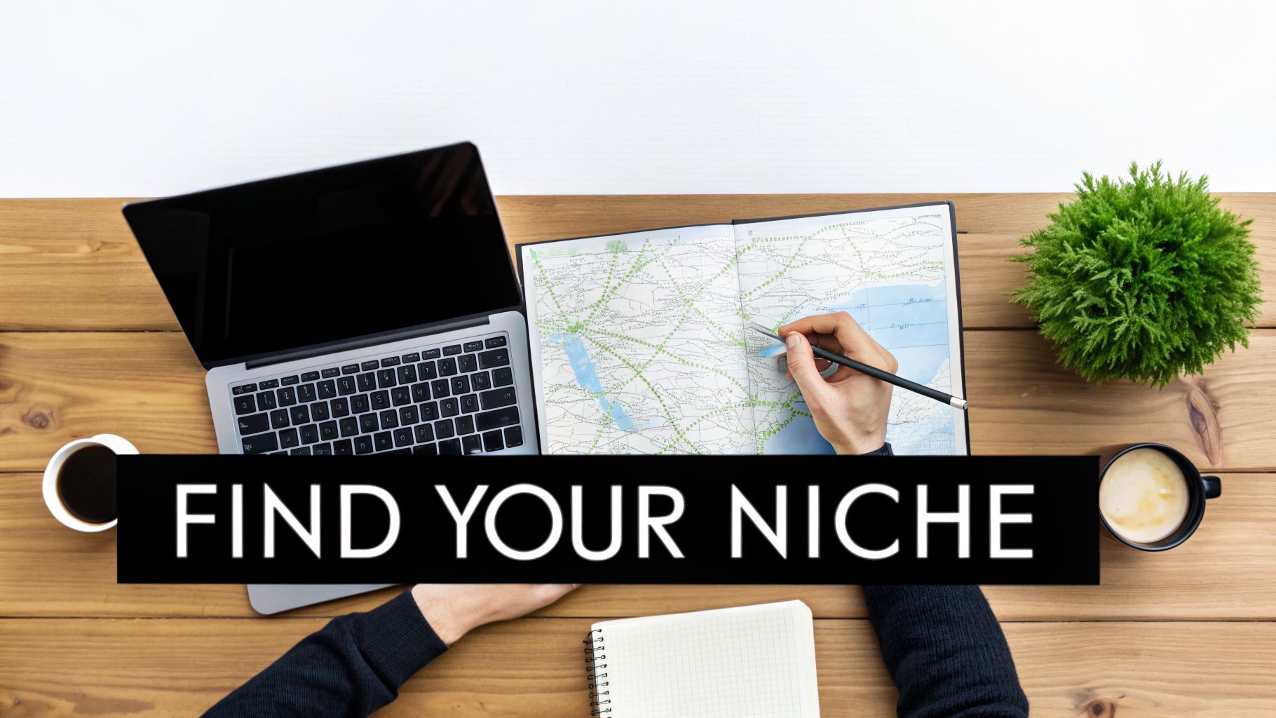 Overhead shot of a person planning on a map next to a laptop and coffee cups on a desk.